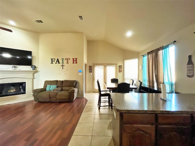 kitchen with vaulted ceiling, light tile patterned floors, a wealth of natural light, and dark brown cabinets