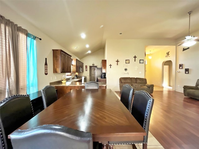 dining space with ceiling fan, vaulted ceiling, and light hardwood / wood-style flooring