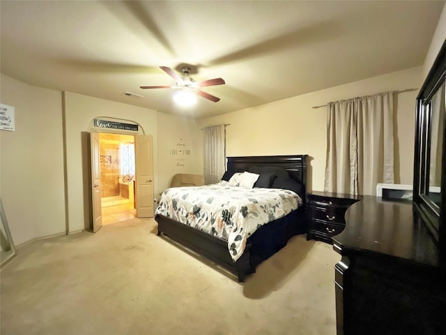 bedroom with ceiling fan, light colored carpet, and connected bathroom