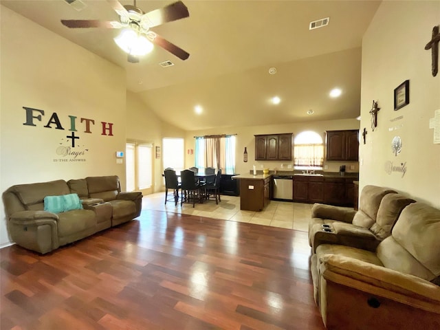 living room with light wood-type flooring, ceiling fan, high vaulted ceiling, and sink