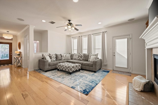 living room with ceiling fan, hardwood / wood-style floors, crown molding, and a fireplace