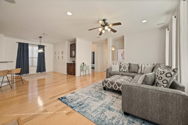 living room with ceiling fan, wood-type flooring, and ornamental molding