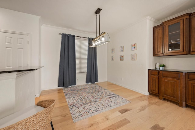 dining space featuring light wood-type flooring and crown molding