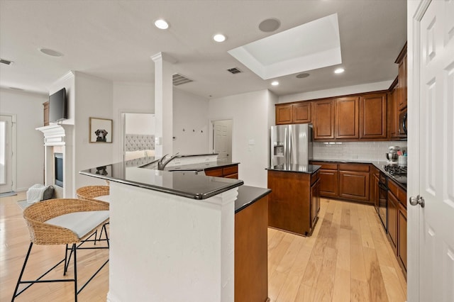 kitchen featuring a center island, tasteful backsplash, sink, stainless steel fridge, and light wood-type flooring