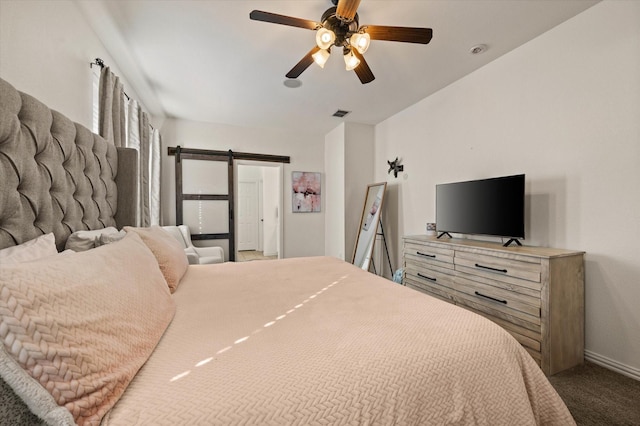 bedroom with ceiling fan, carpet, and a barn door