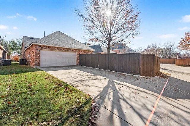 view of side of home featuring a garage, central air condition unit, and a lawn