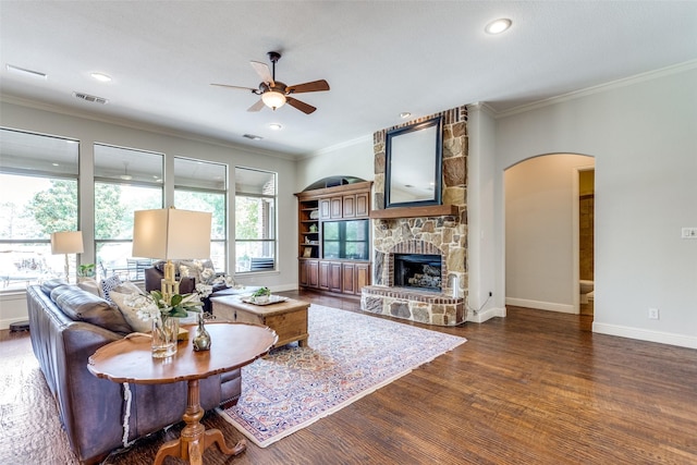 living room with dark wood-type flooring, plenty of natural light, a stone fireplace, and ceiling fan