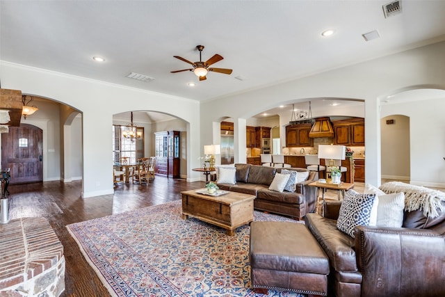 living room with ceiling fan with notable chandelier, dark hardwood / wood-style flooring, and crown molding