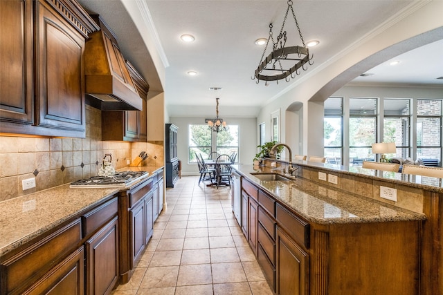 kitchen featuring light tile patterned floors, stainless steel appliances, a notable chandelier, light stone counters, and sink