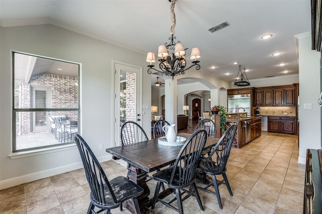 dining room with sink, ornamental molding, lofted ceiling, and a chandelier