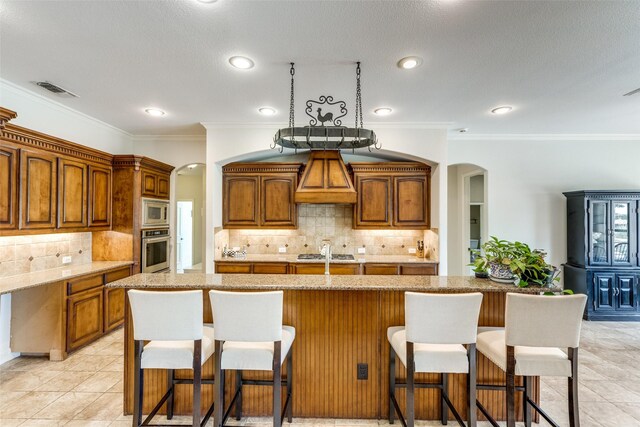kitchen featuring arched walkways, tasteful backsplash, visible vents, and stainless steel appliances