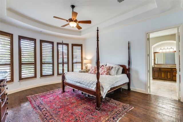 bedroom with ceiling fan, connected bathroom, and a raised ceiling