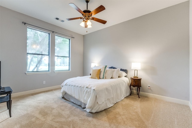 bedroom with baseboards, visible vents, and light colored carpet
