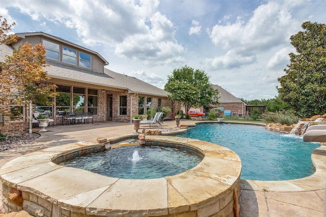 view of swimming pool with a water slide, a patio, and a pool with connected hot tub
