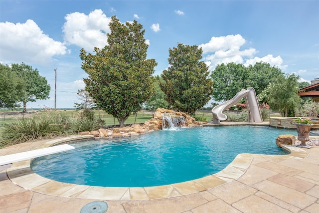 view of pool with a diving board, pool water feature, a patio, and a water slide