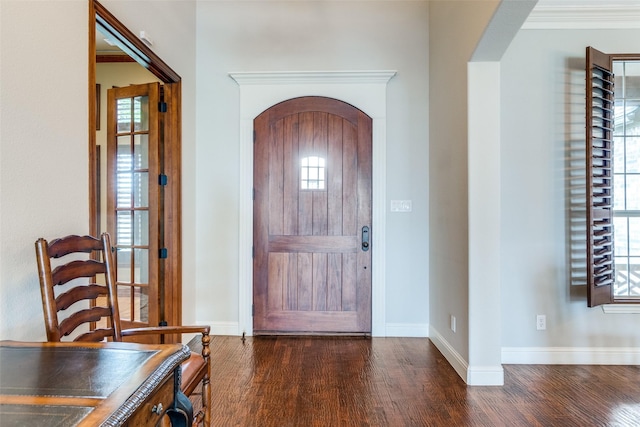 foyer featuring dark wood-type flooring, a wealth of natural light, and ornamental molding