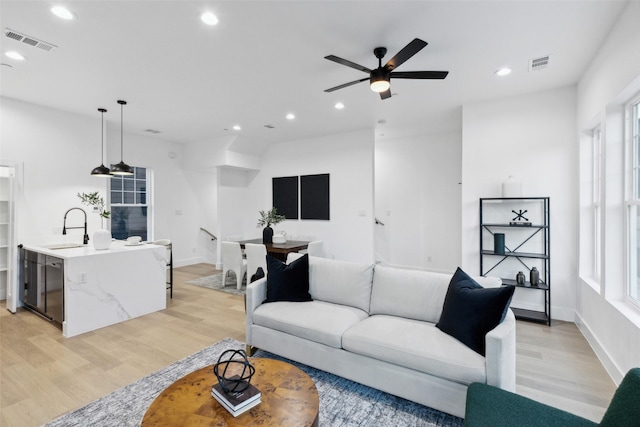 living room featuring ceiling fan, plenty of natural light, sink, and light hardwood / wood-style flooring