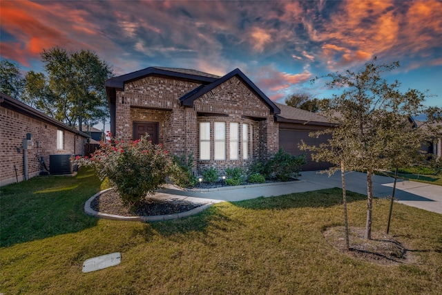 view of front of house with central AC, a yard, and a garage