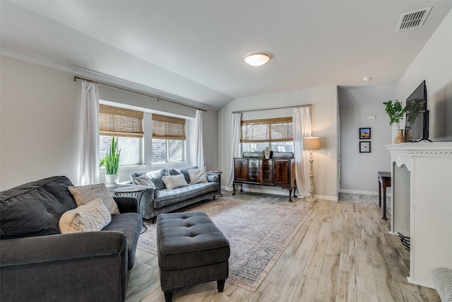 living area featuring visible vents, light wood finished floors, and baseboards