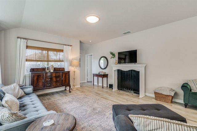 living area with lofted ceiling, visible vents, wood finished floors, and baseboards