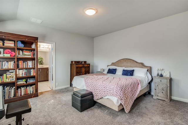 carpeted bedroom with lofted ceiling and ensuite bath