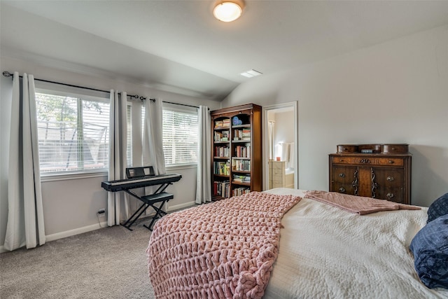 carpeted bedroom featuring ensuite bath, multiple windows, and lofted ceiling