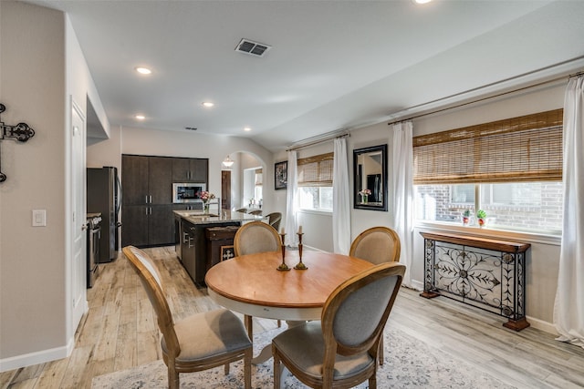 dining room featuring light hardwood / wood-style flooring and vaulted ceiling