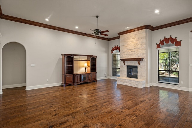 unfurnished living room featuring a fireplace, dark wood-type flooring, ornamental molding, and ceiling fan