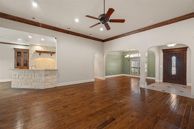 unfurnished living room with crown molding, ceiling fan with notable chandelier, and dark hardwood / wood-style flooring