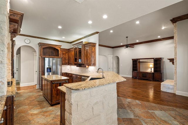 kitchen with sink, ceiling fan, appliances with stainless steel finishes, a center island, and kitchen peninsula