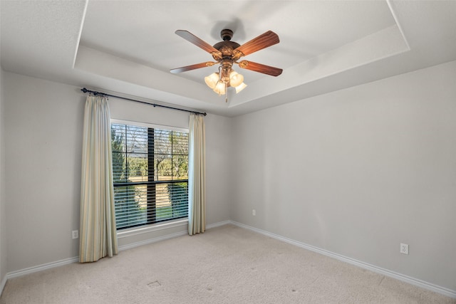 carpeted empty room with ceiling fan and a raised ceiling