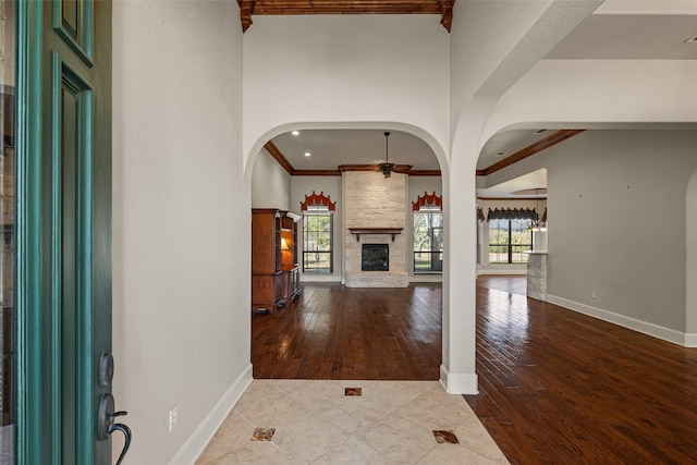 entrance foyer featuring ceiling fan, plenty of natural light, a fireplace, and ornamental molding