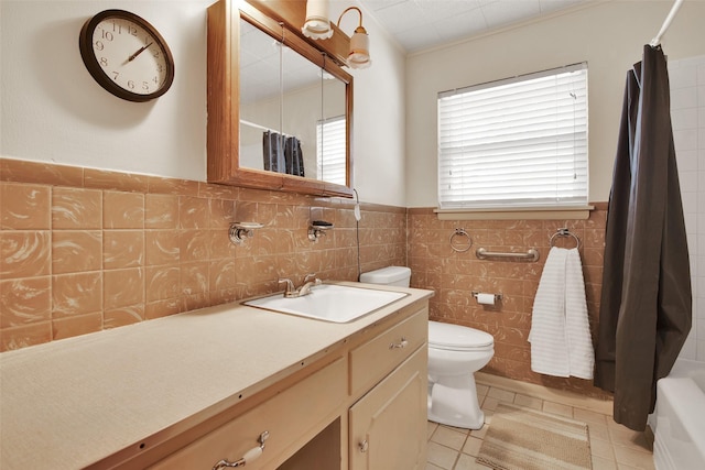 bathroom with toilet, tile patterned flooring, tile walls, and vanity