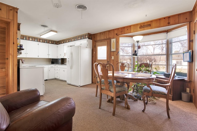 carpeted dining area featuring wooden walls