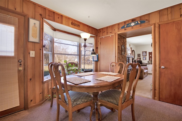 dining room with light colored carpet and wooden walls