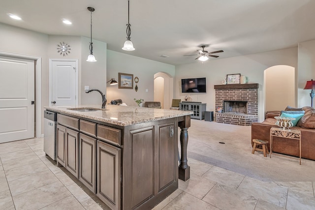 kitchen featuring a center island with sink, ceiling fan, decorative light fixtures, a fireplace, and sink