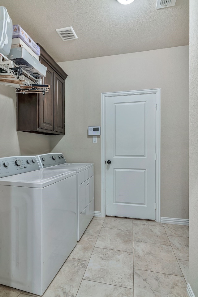 laundry area featuring cabinets, a textured ceiling, and washer and clothes dryer