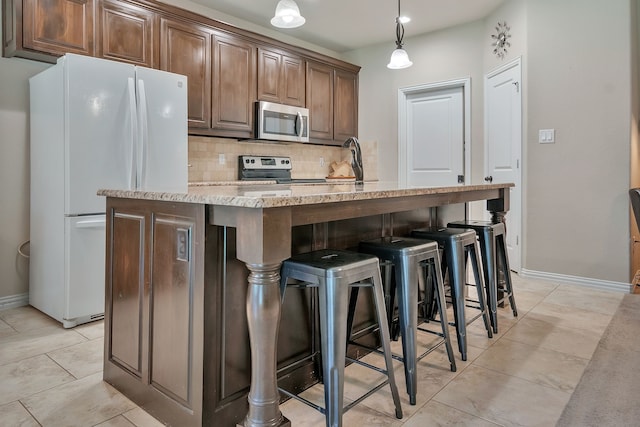 kitchen featuring decorative backsplash, sink, hanging light fixtures, a kitchen island with sink, and stainless steel appliances