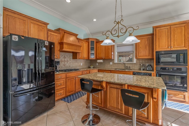 kitchen featuring premium range hood, a kitchen bar, decorative light fixtures, a kitchen island, and black appliances