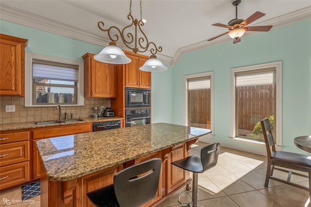 kitchen with a kitchen bar, decorative light fixtures, sink, ornamental molding, and black appliances