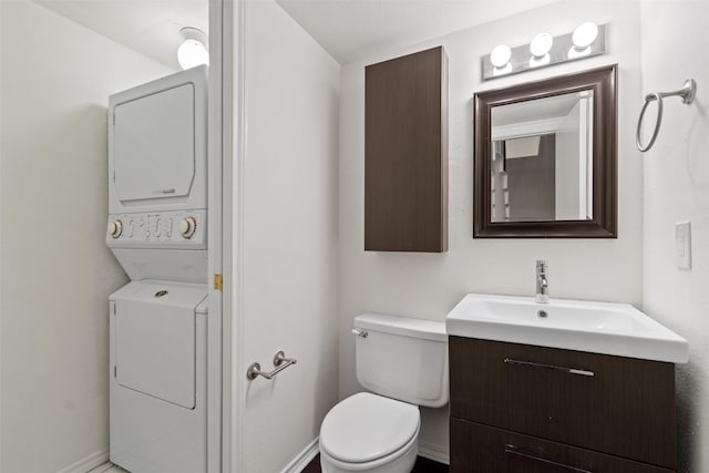 bathroom with toilet, stacked washer / dryer, and vanity