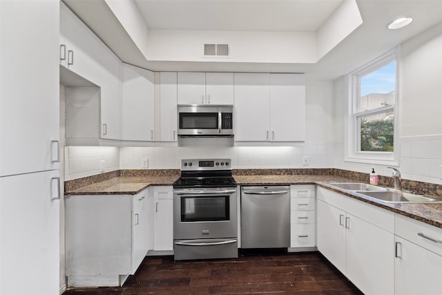 kitchen with backsplash, sink, white cabinetry, stainless steel appliances, and dark hardwood / wood-style flooring