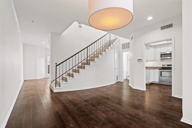 unfurnished living room featuring dark wood-type flooring and crown molding