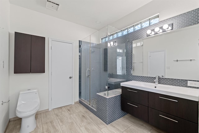 bathroom with toilet, vanity, backsplash, and a shower with door