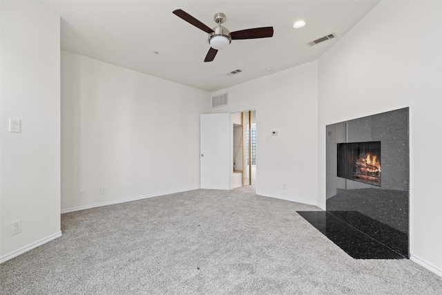 unfurnished living room featuring ceiling fan, a fireplace, and carpet flooring