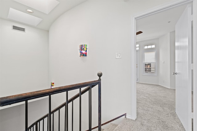 hallway featuring light colored carpet and a skylight