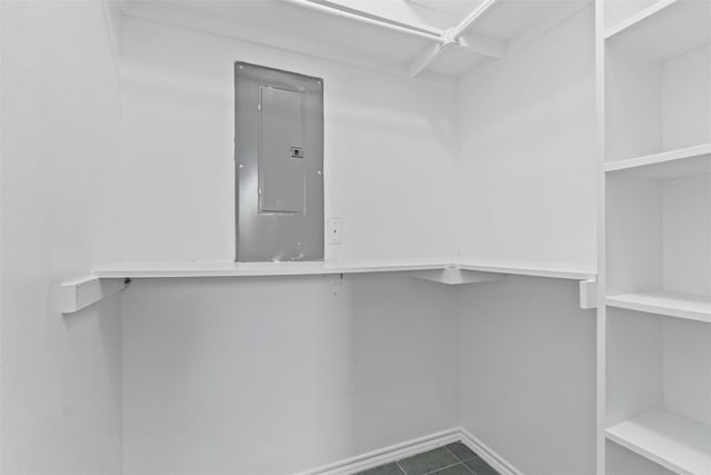 walk in closet with electric panel and dark tile patterned flooring