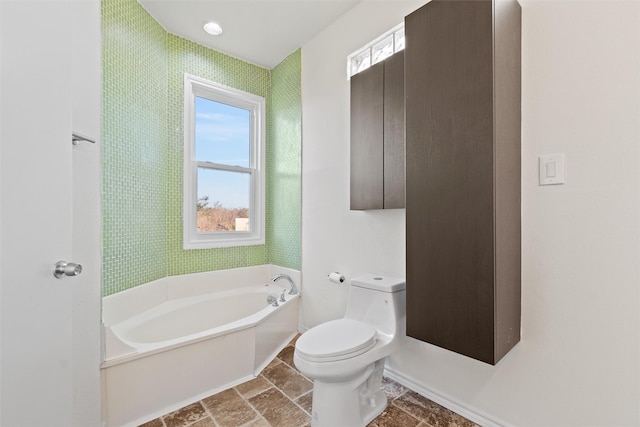 bathroom featuring toilet, a bathing tub, and a wealth of natural light