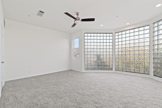 carpeted empty room with ceiling fan and plenty of natural light