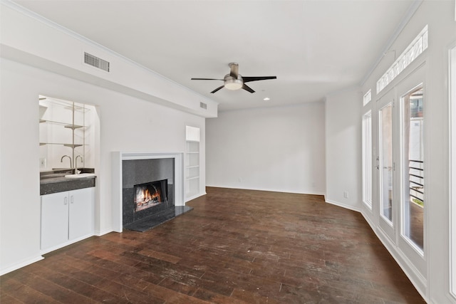 unfurnished living room with ceiling fan, dark hardwood / wood-style flooring, a wealth of natural light, and ornamental molding